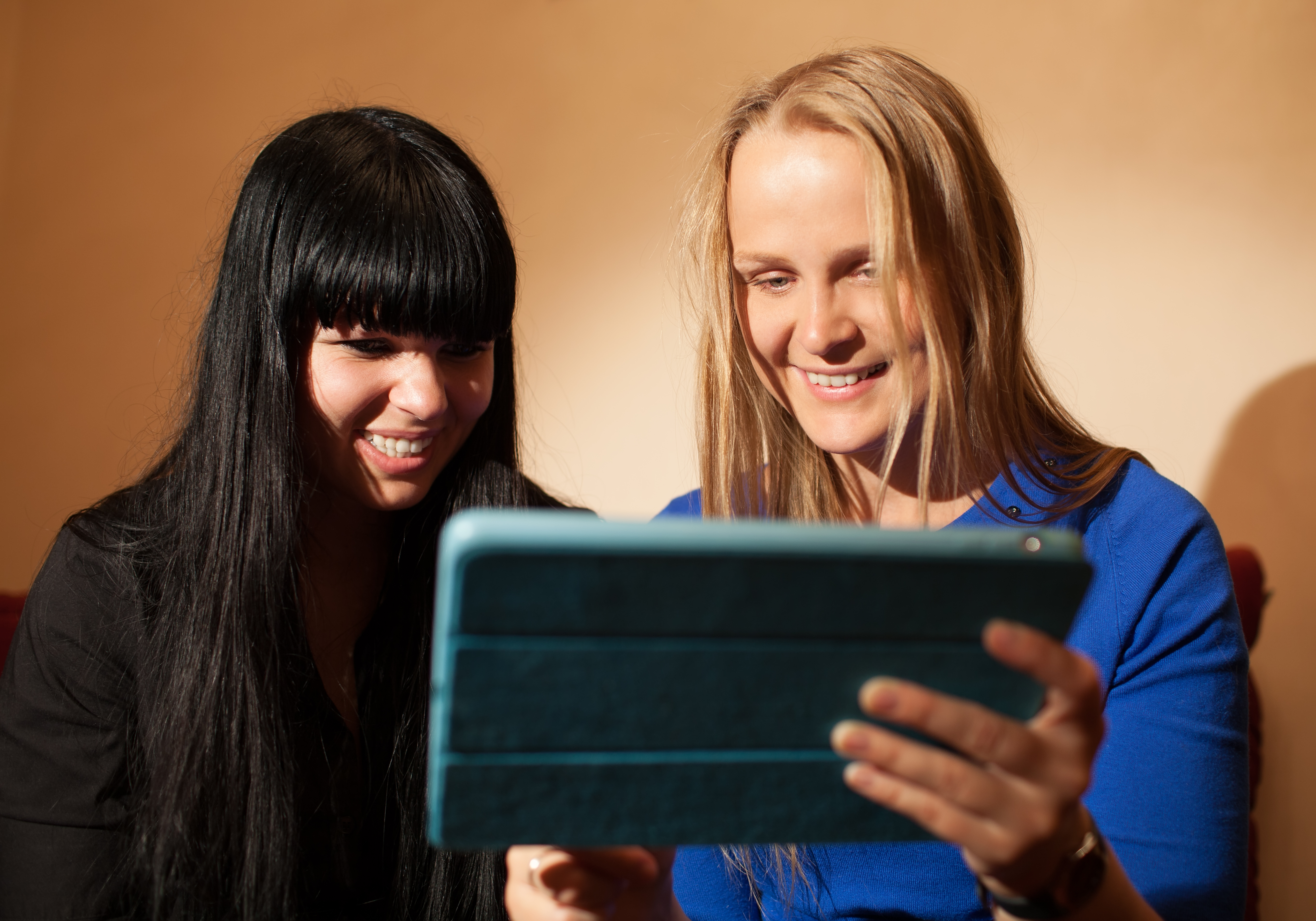 Two young woman reading a tablet-pc