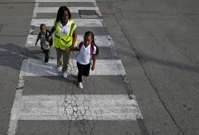 Safe Passage worker Irene Fonder helps two Sherwood Elementary School children cross an intersection in the Englewood neighborhood in Chicago, Illinois, United States