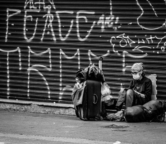 Barn som forsvinner fra asylmottak kan bli ofre for menneskehandel Unrecognizable tourist in mask with suitcase near graffiti wall