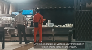 Arlen Khadaa kjøper mat i kantina på utsiden av transittsonen på flyplassen mens vakten holder øye med ham.