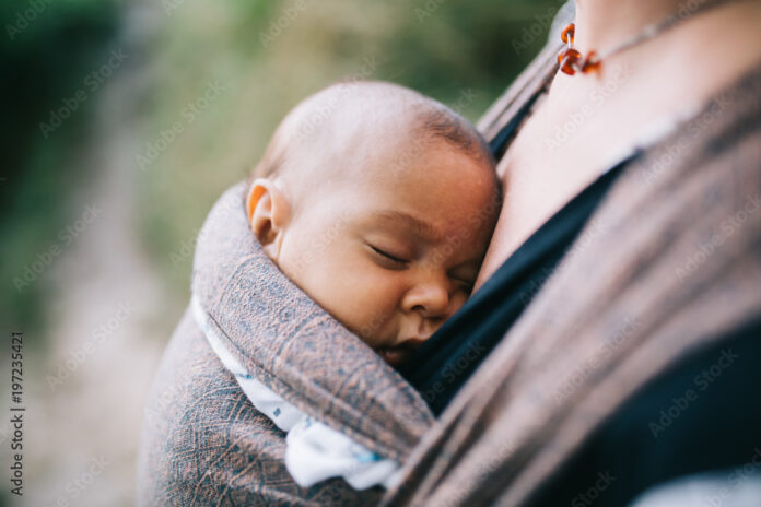 blonde-caucasian-mom-holding-her-colored-child-in-a-sling-stockpack-adobe-stock Blonde caucasian mom holding her colored child in a sling