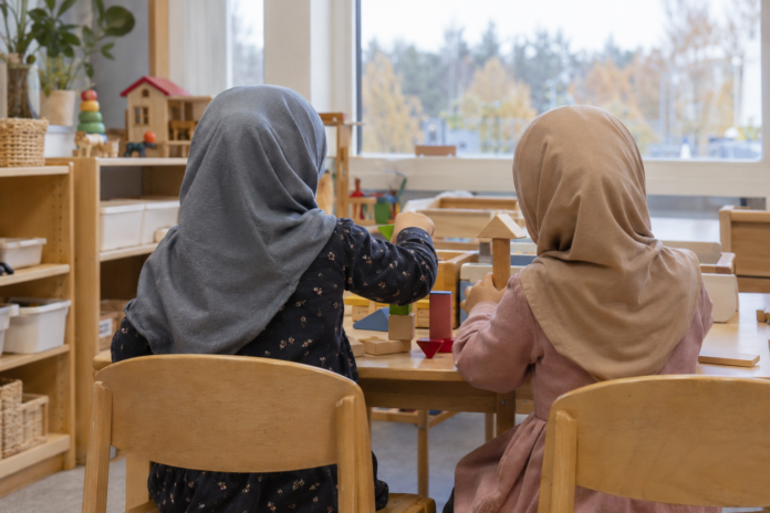 Two hijab-wearing children build blocks